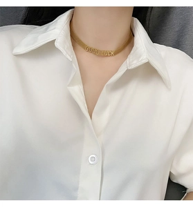 Détail du collier choker doré Good Luck sur femme portant un chemisier en soie