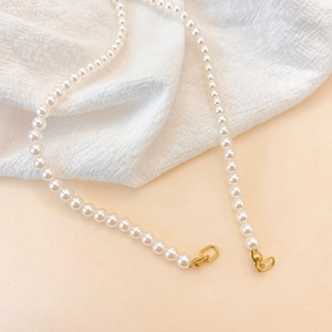 Detail of high-gloss pearls and gold stainless steel clasp on soft pink background