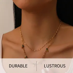Close-up of double-layered gold plated necklace with green beads and round charms on neck