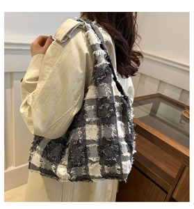 Detailed view of the checkered tote bag with fringe edge details and tweed texture on model