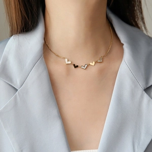 Elegant gold titanium necklace with black and white heart pendants on a female model