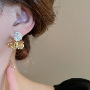 Artistic two-tone gold and silver pleated flower earrings worn by a female model