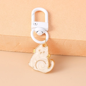 Close-up of cute white enamel cat keychain with elegant gold metal frame and spring clasp