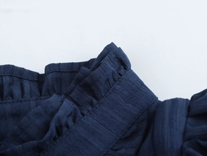 Close-up of navy blue blouse showing ruffled waist detail and textured woven fabric