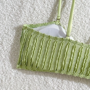 Detail eines hellgrünen Bikini-Tops mit Wellenstruktur und verstellbaren Trägern