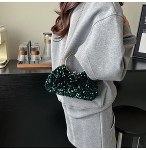 Detail of dark green sequined evening bag with golden ring handle and metal chain
