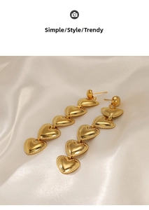 Detail of five linked gold heart drop earrings on elegant white satin background