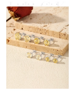 Macro shot of S925 silver stud earrings with yellow round-cut stones on travertine
