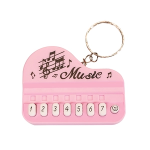Pink piano keychain musical toy with digital keys and gold metal ring on white background