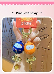 Close-up of lucky cat bell keychains in blue and orange with gold accents