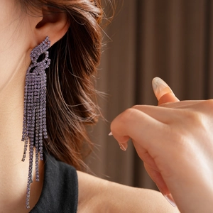 Gros plan d'un mannequin portant des boucles d'oreilles à pompons en strass violets fins