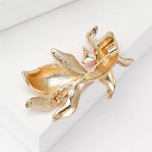 Elegant gold enamel goldfish brooch with textured metallic finish on a white pedestal