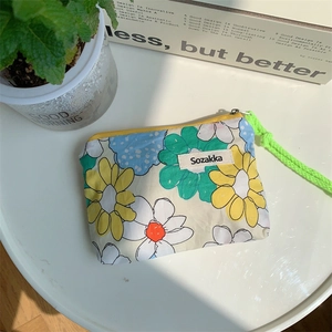 Close-up of floral canvas cosmetic bag with neon green woven zipper puller on table
