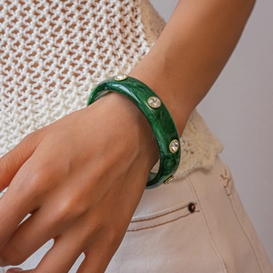 Detail of green marble acrylic bracelet with gold-framed sparkling crystal rhinestones