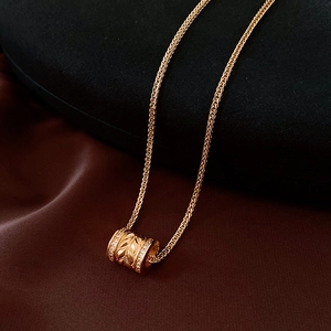 Macro view of 24k gold-plated cylinder pendant with leaf texture and pavé zircons