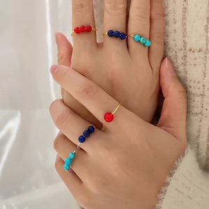 Detail showing stacked gold and silver wire rings with red blue and turquoise beads