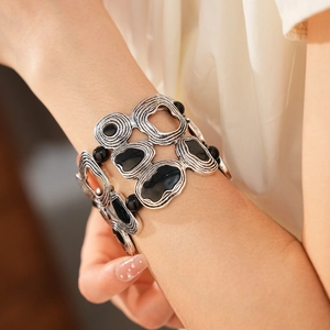 Close-up of vintage geometric elastic bracelet with spiral textures and black resin inlay