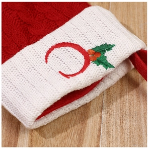 Close-up of red knitted Christmas stocking with embroidered letter C and holly berries