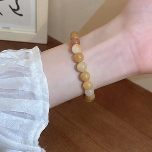 Close-up of yellow translucent bead bracelet worn by a model against wooden background