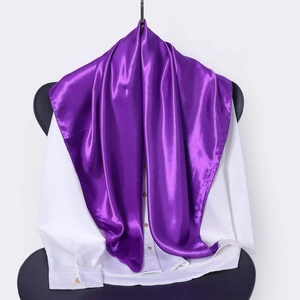 Detail showing smooth purple satin silk scarf draped over a white shirt on a chair