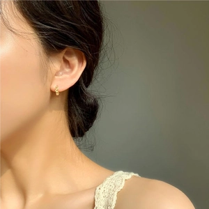 Close-up of a model wearing small gold chain hoop earrings made of 925 sterling silver