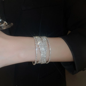 Macro shot of silver-tone layered bracelet with pavé rhinestones on model sleeve