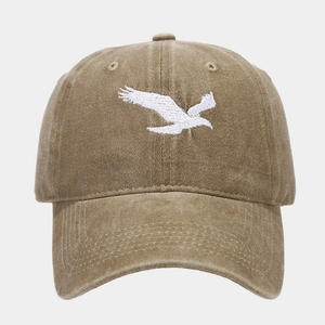 Close-up detail showing the white eagle embroidery on a washed khaki distressed baseball cap