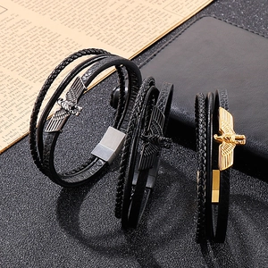 Détail de trois bracelets en cuir multicouches avec aigles en or, argent et noir mat