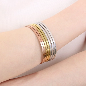 Detail of stacked rose gold, gold, and silver open cuffs on model's wrist