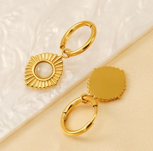 Détail macro de pendentifs soleil dorés avec perles d'opale sur créoles polies de luxe