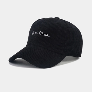 Detail shot of black corduroy baseball cap showing white 'baba' embroidery and texture