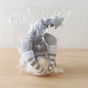 Detail view of a grey knitted Christmas gnome with snowflake pattern in protective packaging