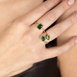 Detail view of emerald green rectangular and teardrop cut zircon rings on hand