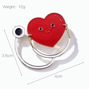 Détail de la broche stéthoscope cœur en émail rouge avec smiley, mesure 4cm x 3,6cm