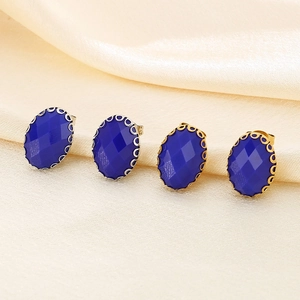 Detail of blue oval glass earrings with ornate gold and silver basket claw settings