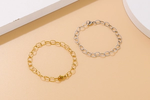 Detail view of gold and silver hollow oval chain link bracelets on a minimalist background