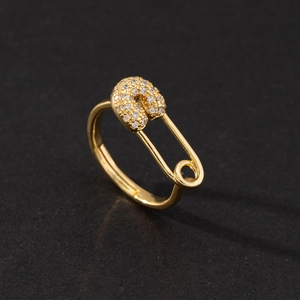Detail shot of a polished gold safety pin ring encrusted with micro-pave zircons