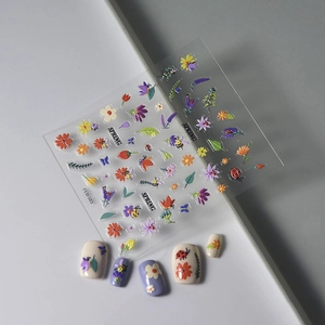 Macro view of 5D spring nail stickers featuring colorful daisies, bees and floral patterns