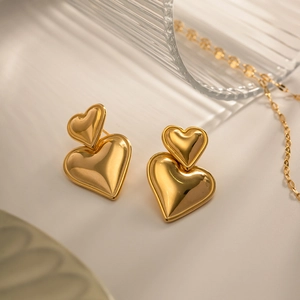Macro shot of double-layer heart-shaped gold earrings with a high-polished mirror finish