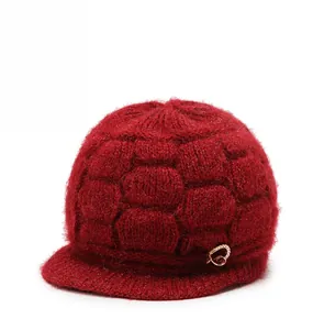 Detailed view of dark red knit hat featuring honeycomb texture and golden bow brooch