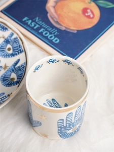 Detailed close-up of Hamsa and Evil Eye patterns on ceramic mug with gold-rimmed edge