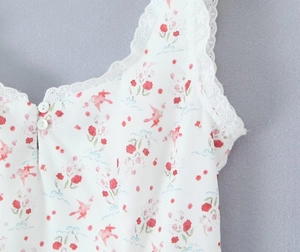 Detalle del vestido blanco con estampado floral, encaje delicado y botones frontales