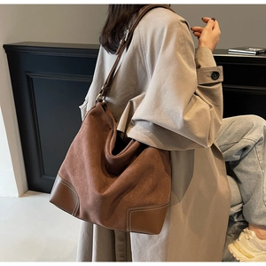 Detail view of brown suede hobo bag with leather patchwork and white stitching
