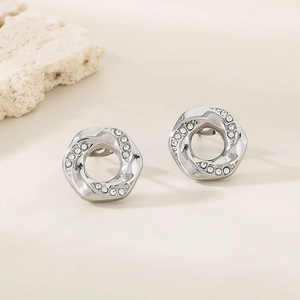 Macro shot of silver geometric stud earrings with sparkling crystals on natural stone