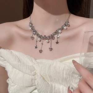 Gros plan d'un collier argenté avec perles, étoiles et papillon violet sur un mannequin