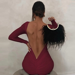 Detail of burgundy backless dress showing deep V-back design and black feather clutch bag