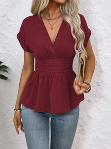 Detail of wine red V-neck top showing ruffled hem and pleated waist fabric texture