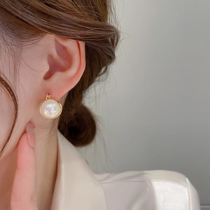 Close-up of elegant gold rimmed pearl hoop earrings worn by a model for a minimalist style