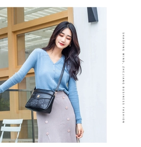 Close-up view of womens black floral embossed crossbody shoulder bag with metal decor.