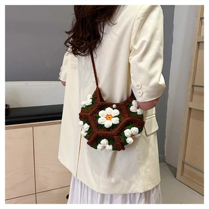 Detailed knit texture of a brown crochet shoulder bag with white 3D floral daisies